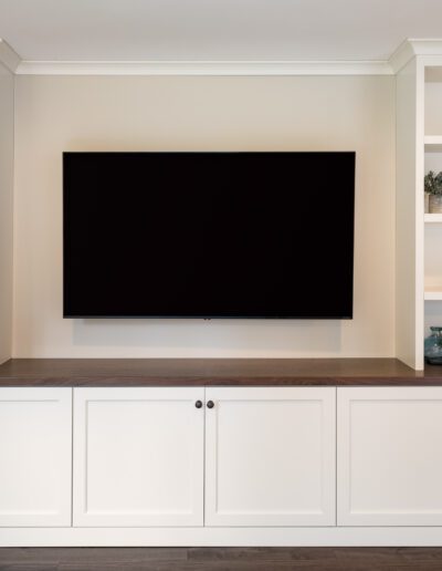 A white entertainment center with shelves and a tv.
