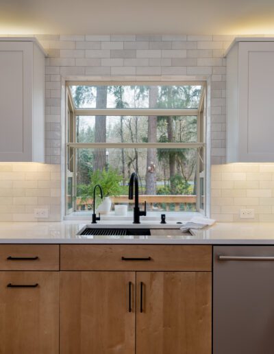 A white kitchen with wood cabinets and a window.