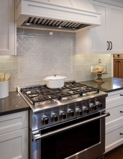 A white kitchen with a stainless steel stove top.