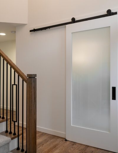 A sliding barn door in a home with stairs.