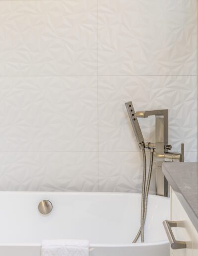 A bathroom with a white tub and white tiled walls.