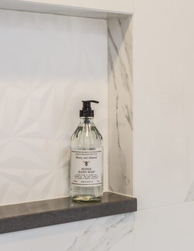A bottle of soap sits on a shelf in a bathroom.