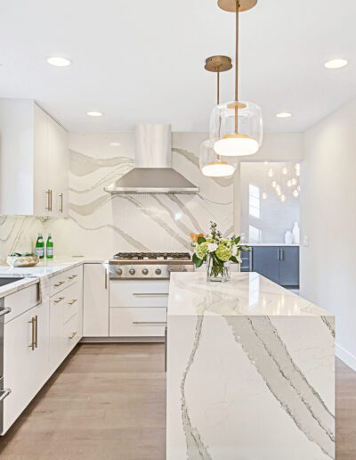 A white kitchen with stainless steel appliances and marble counter tops.