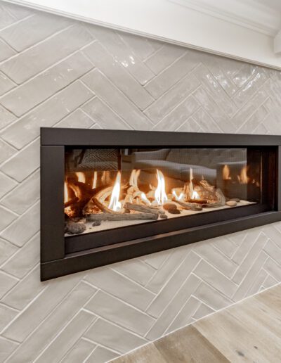 A fireplace in a living room with tiled walls.