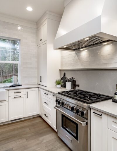 A white kitchen with stainless steel appliances and a window.