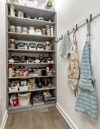 A kitchen pantry with pots and pans hanging on the wall.