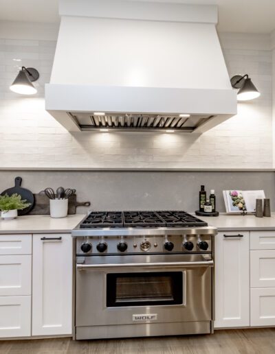A white kitchen with a stainless steel range hood.