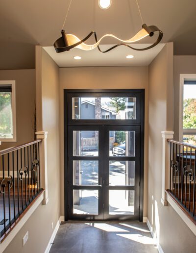 A hallway with a black railing and a light fixture.