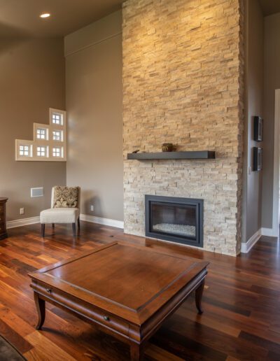 A living room with hardwood floors and a stone fireplace.