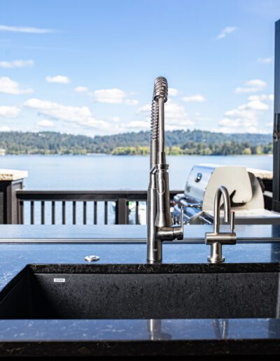 A kitchen sink with a view of a lake.