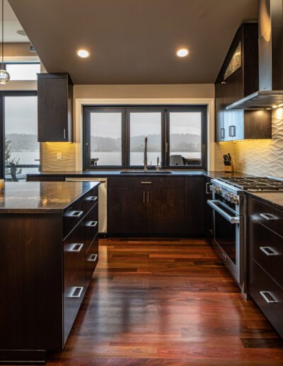 A kitchen with black cabinets and wooden floors.
