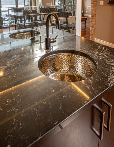 A kitchen with a black granite counter top and a stainless steel sink.