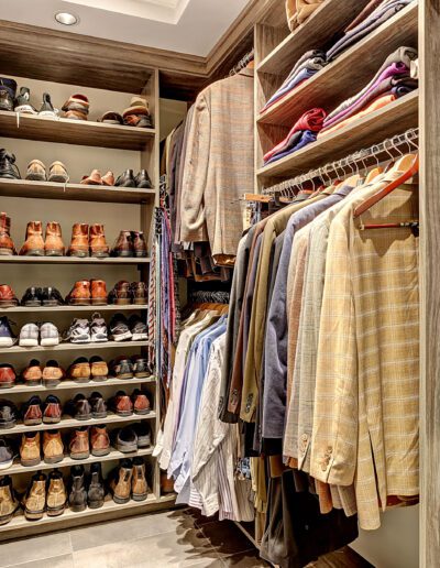 A walk in closet with a lot of clothes and shoes.
