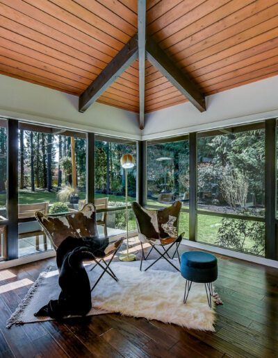 A sunroom with wood floors and a view of a wooded area.