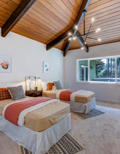Two beds in a bedroom with wood ceilings.