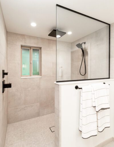 A bathroom with a glass shower stall and a towel rack.