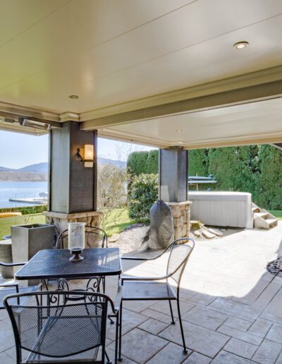 Spacious lakeside patio with outdoor furniture, grill, and hot tub, featuring a scenic lake view.